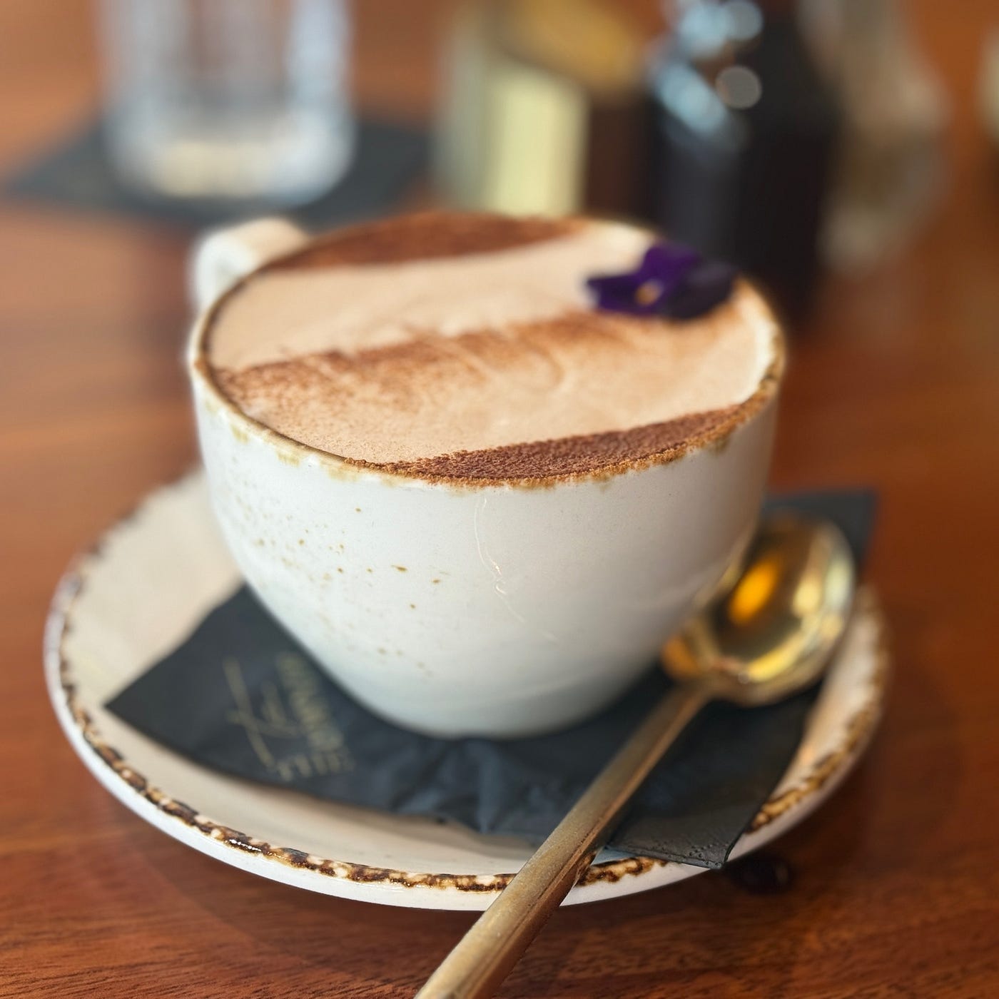 A cup of chai topped with foam and a flower garnish, served at The Corner Lounge