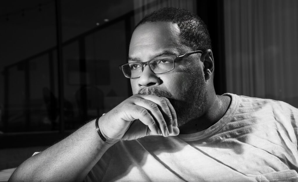 Black and white portrait of Quincy James Freeman, hand on chin, looking out a window, thoughtful expression