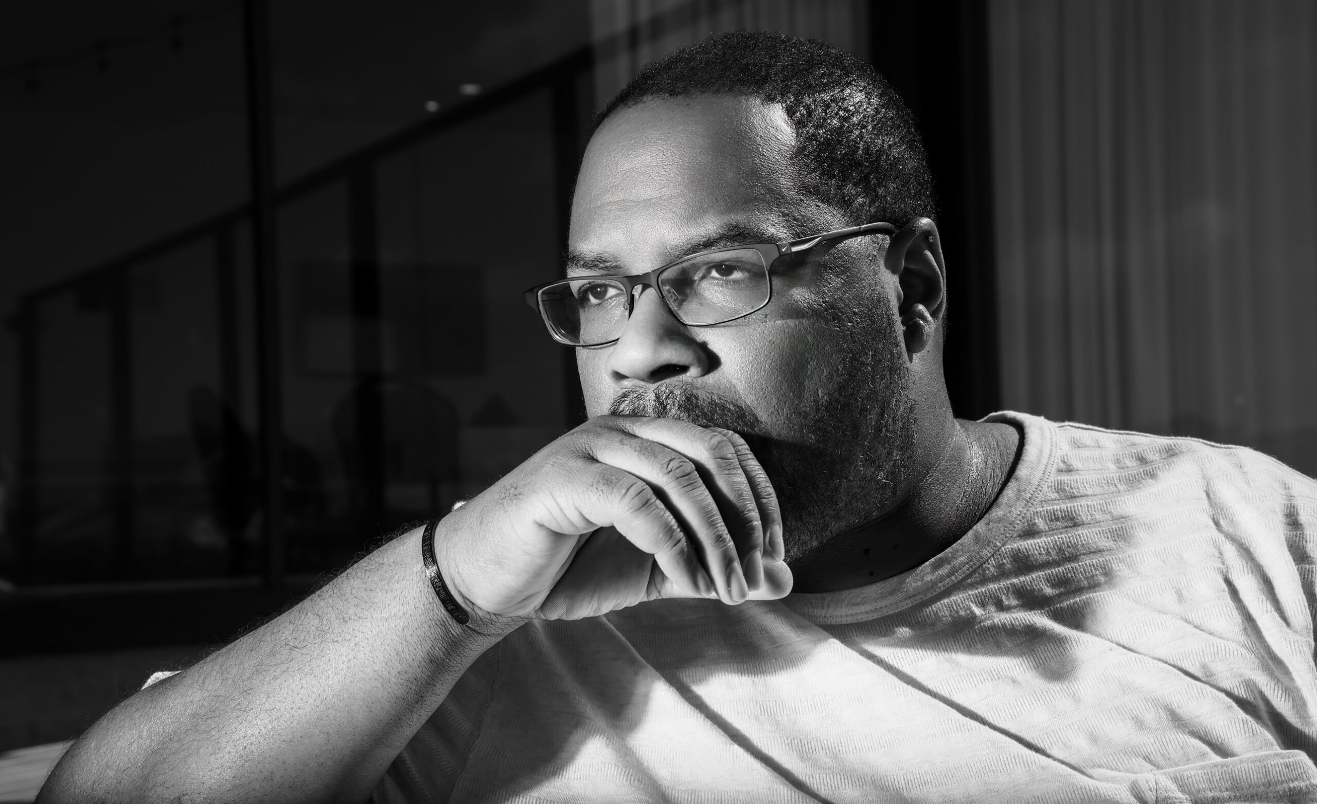 Black and white portrait of Quincy James Freeman, hand on chin, looking out a window, thoughtful expression