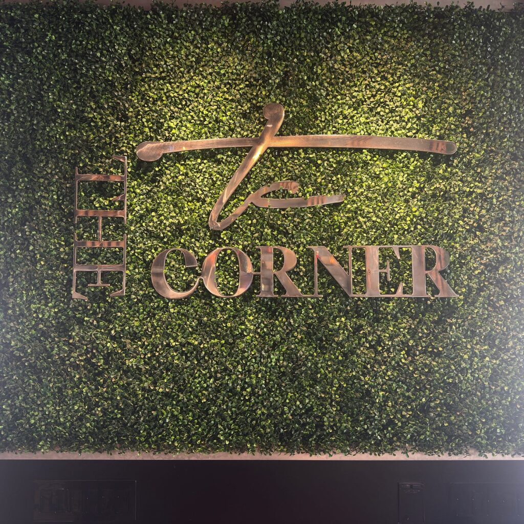 The Corner restaurant logo mounted on a hedge wall
