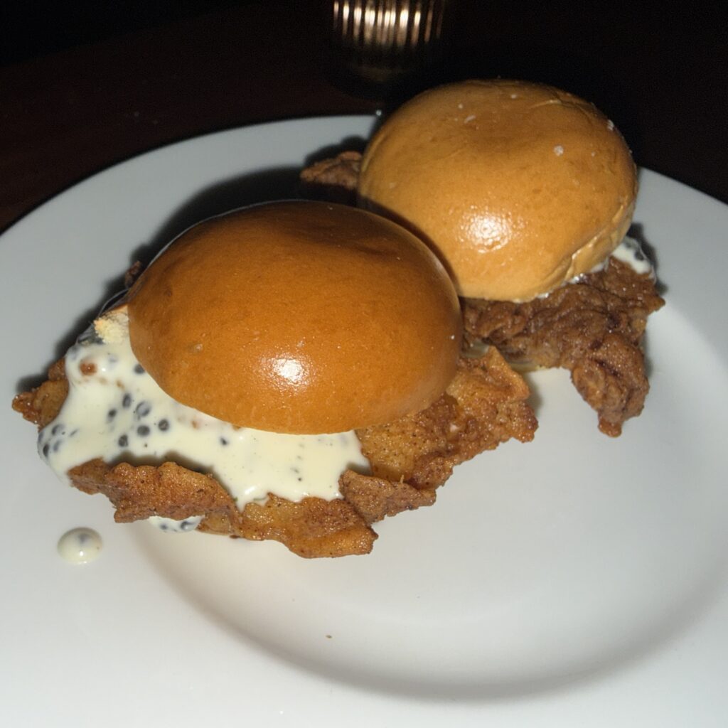 Two fried chicken and caviar sliders on brioche buns, plated at Somerville's dim, candlelit table.
